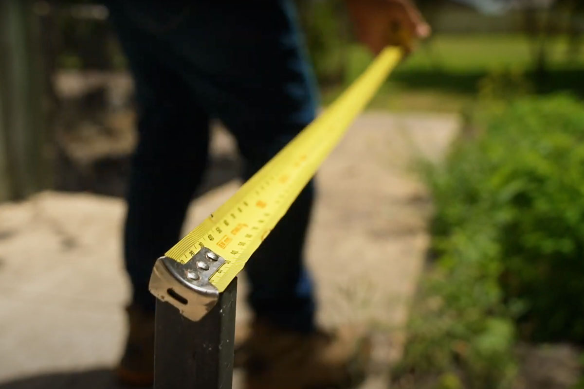 Using a measuring tape to determine the dimensions of the garden bed.